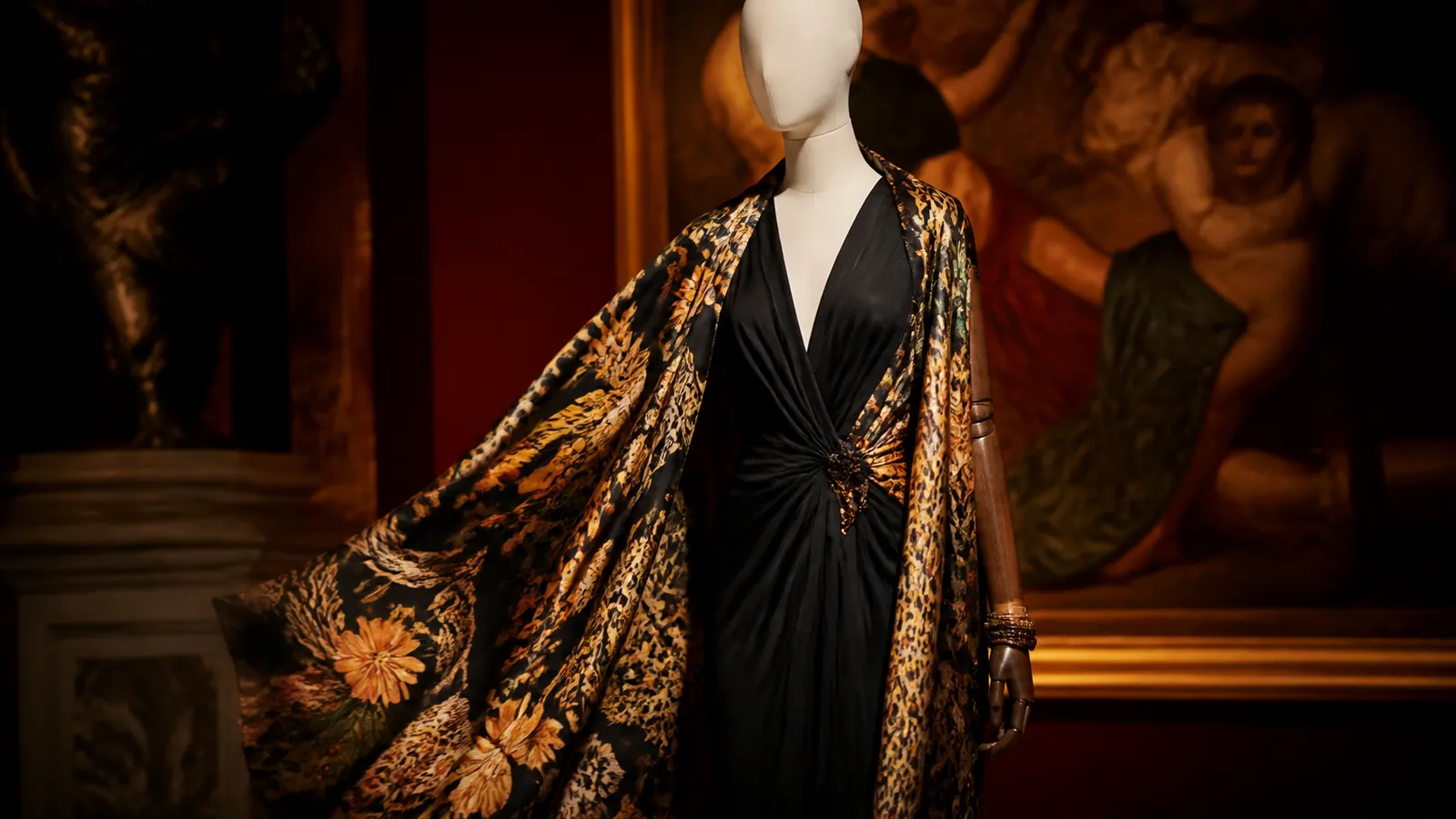 Mannequin portant une silhouette noire avec châle à motif abstrait dans une galerie sombre